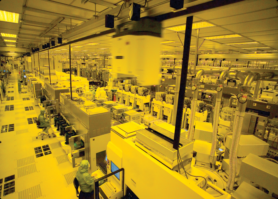 半导体工厂洁净室内景，多排精密设备与穿着无尘服的工作人员