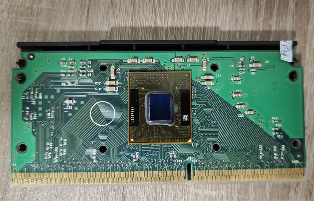 绿色电路板,中央为带蓝色保护盖的方形芯片