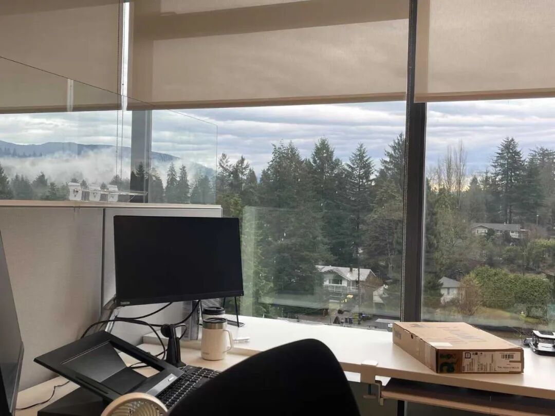 办公室窗边工作台视角，窗外是云雾缭绕的山景