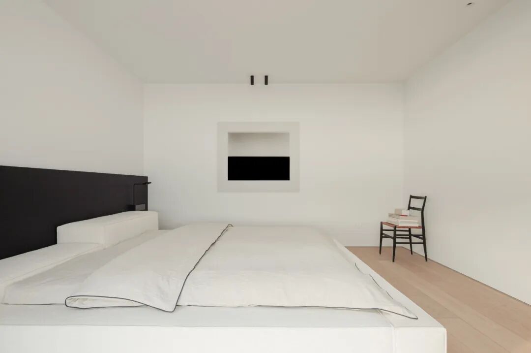 极简风格卧室，黑白抽象画与黑色椅子