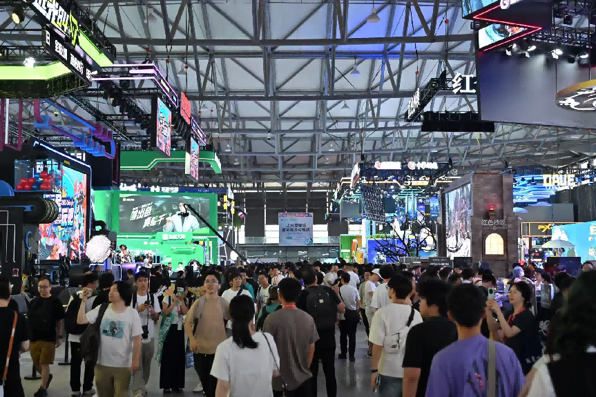大型游戏展会现场，人群密集穿行于各展位之间