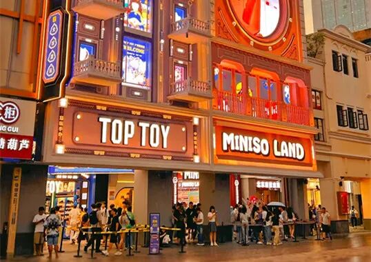 夜晚街景中并排的TOP TOY与MINISO LAND门店