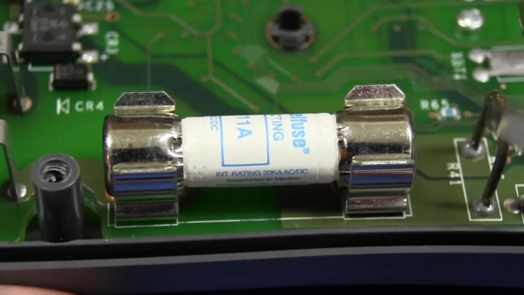 11 A 陶瓷高压熔断器特写,丝印 INT. RATING 20kA AC/DC,两端为镀镍铜帽,装于 PCB 夹簧中