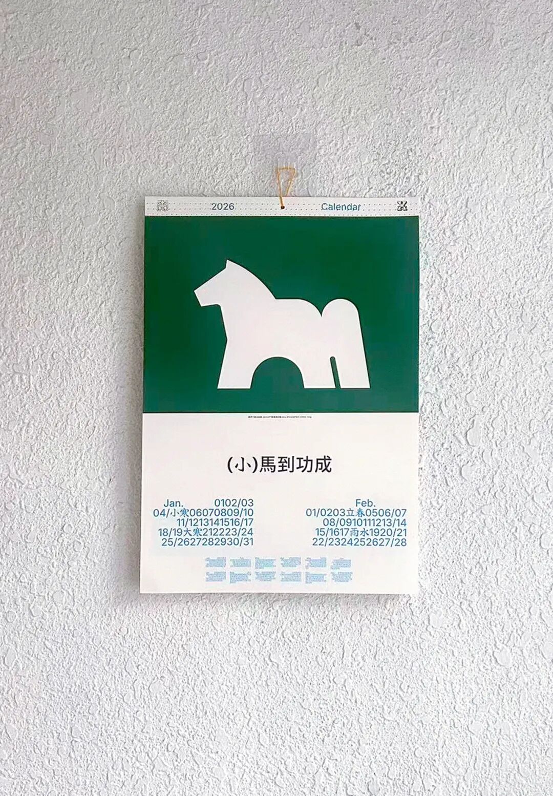 日历挂于墙面，简约现代，绿色背景与白色马形剪影形成鲜明对比