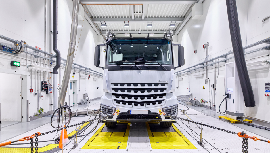 白色重卡停在室内专业测试台上，周围布满测试设备