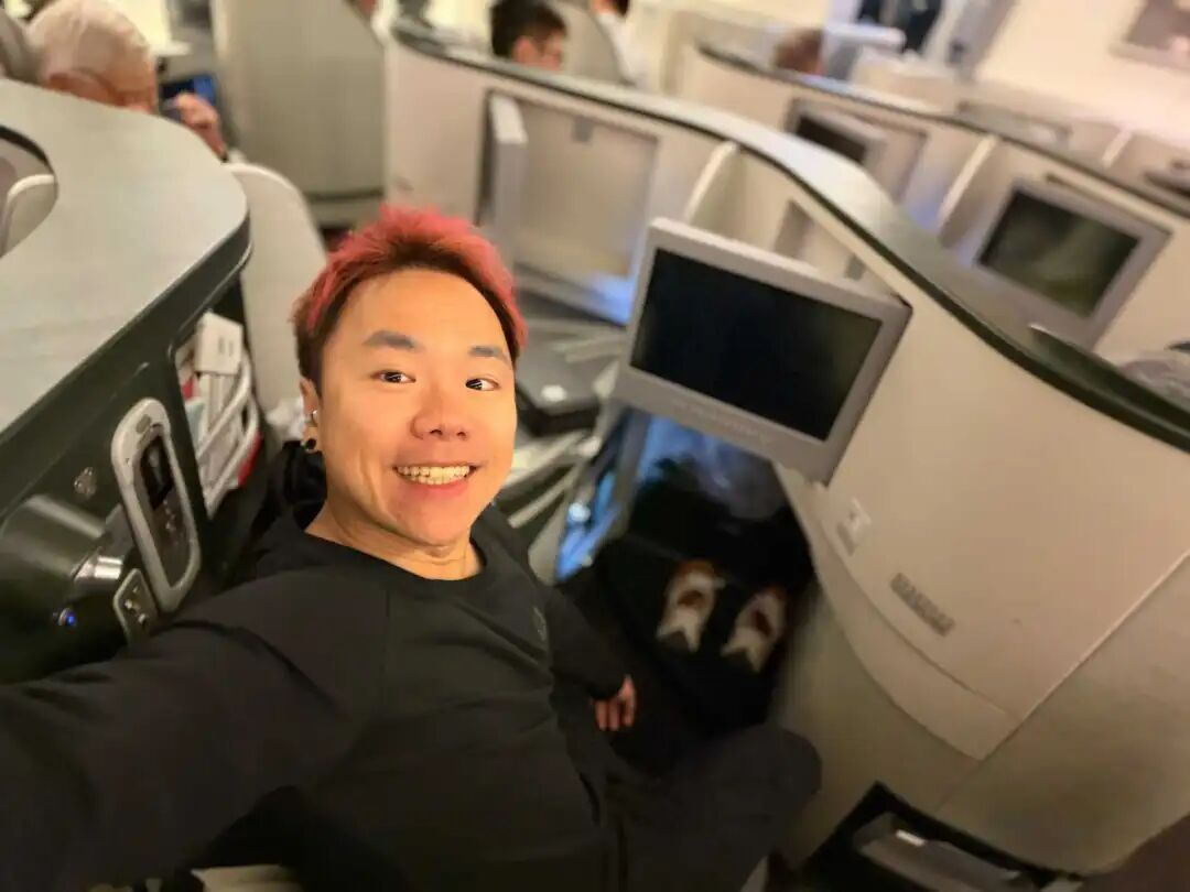 一名染着红发的男子在飞机商务舱微笑自拍