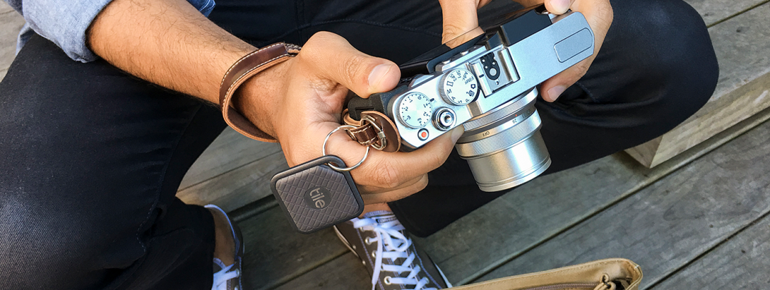 一个人坐在木制地板上，双手握着一台银色复古风格的相机