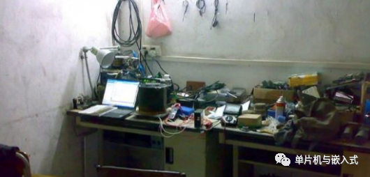 嵌入式硬件开发工作台场景，桌面上摆放着笔记本电脑、电子元件、线缆和调试工具