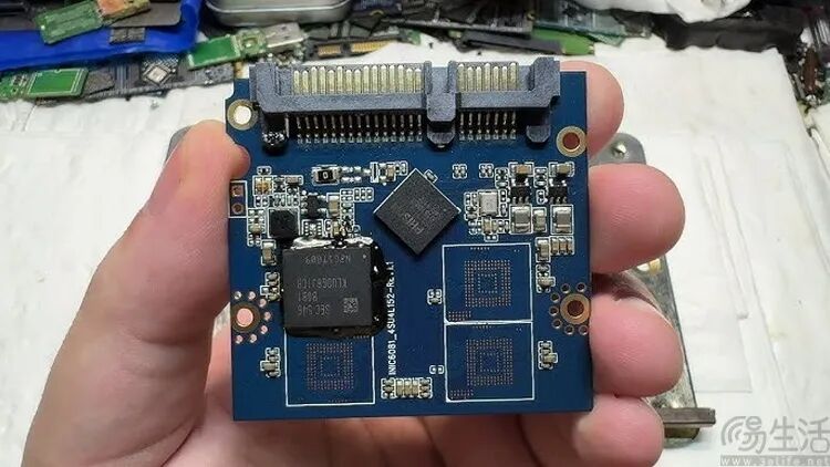 手持蓝色SSD主控板，展示NAND闪存芯片