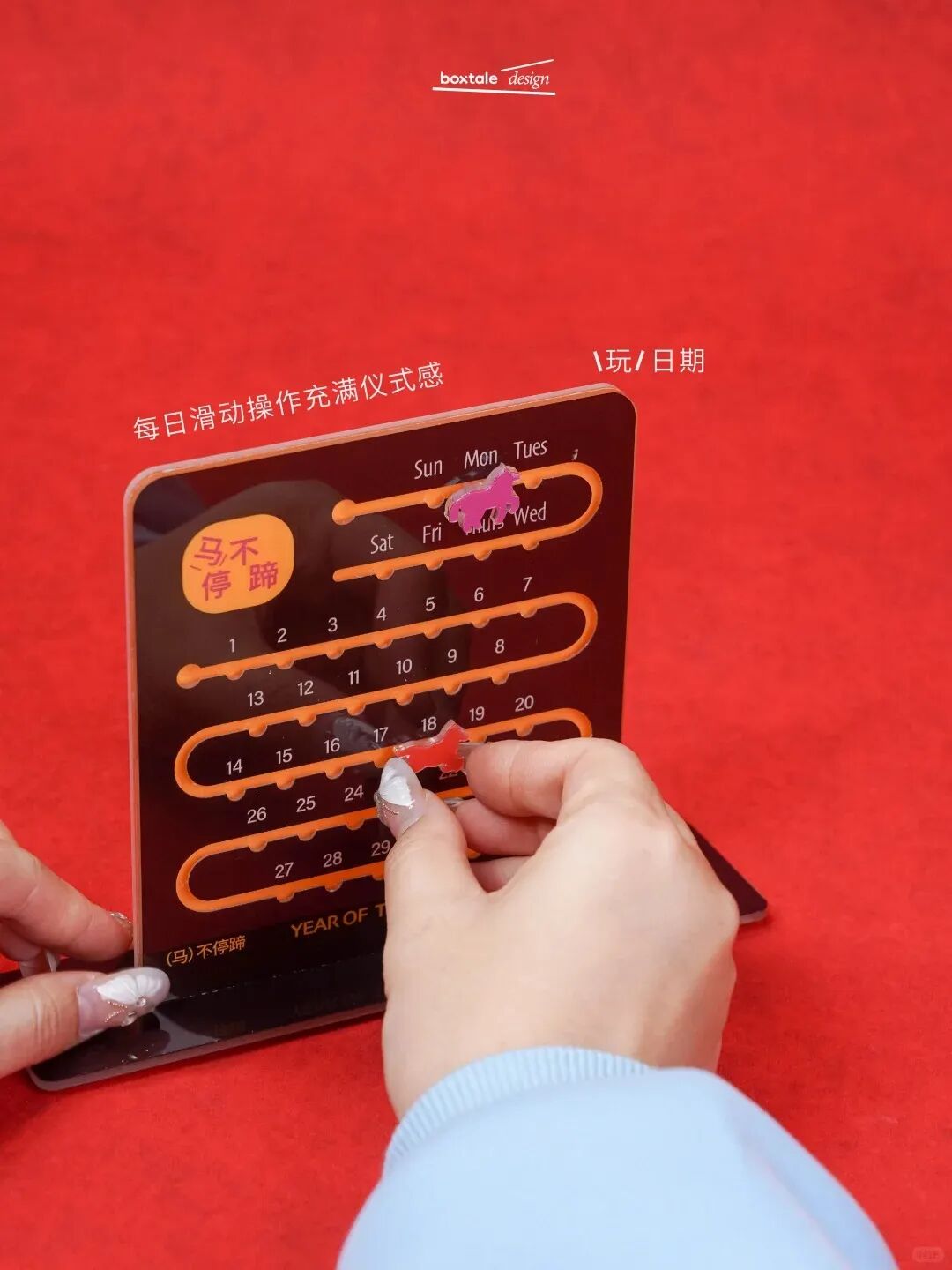 滑动日历特写：透明滑块指向“18”，顶部黄色标签“马不停蹄”，背景红绒布