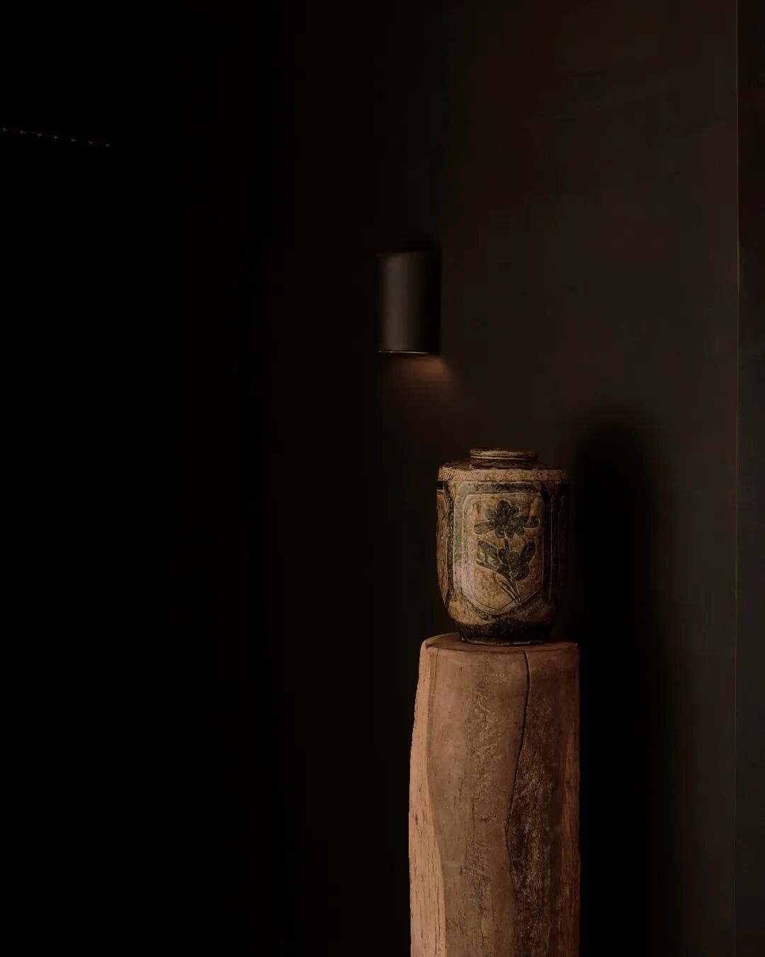 壁灯下，陶罐表面的花卉纹饰特写