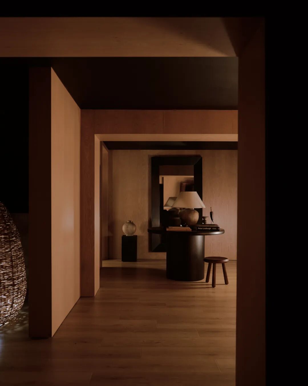 暖色调室内走廊，镜面反射出圆桌与台灯