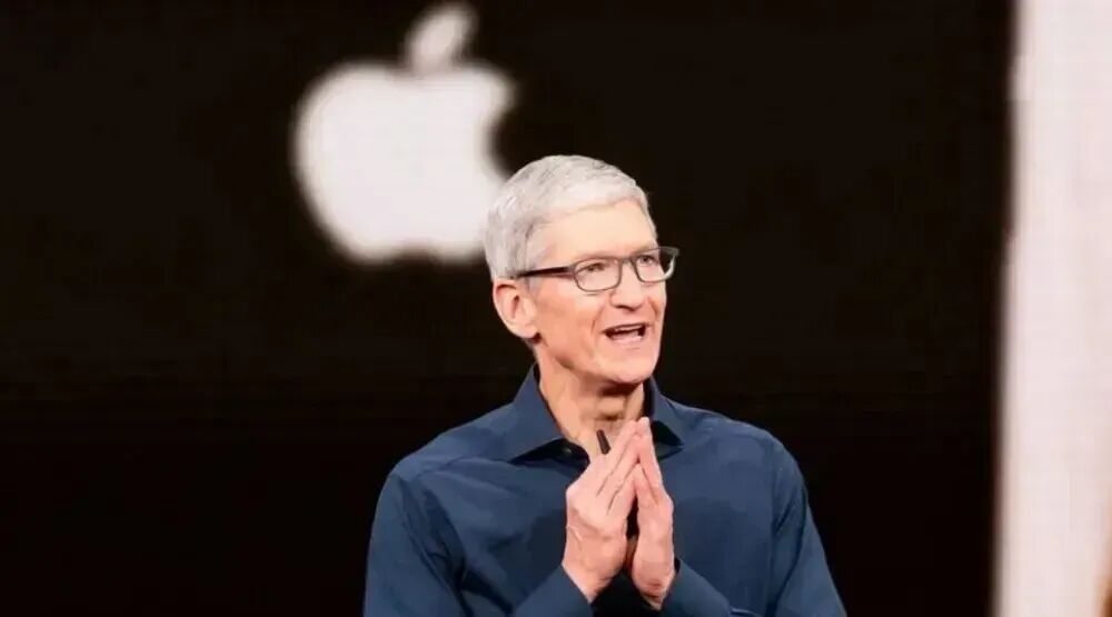 一位白发、戴黑框眼镜的中老年男性站在舞台上演讲致谢，背景为苹果标志