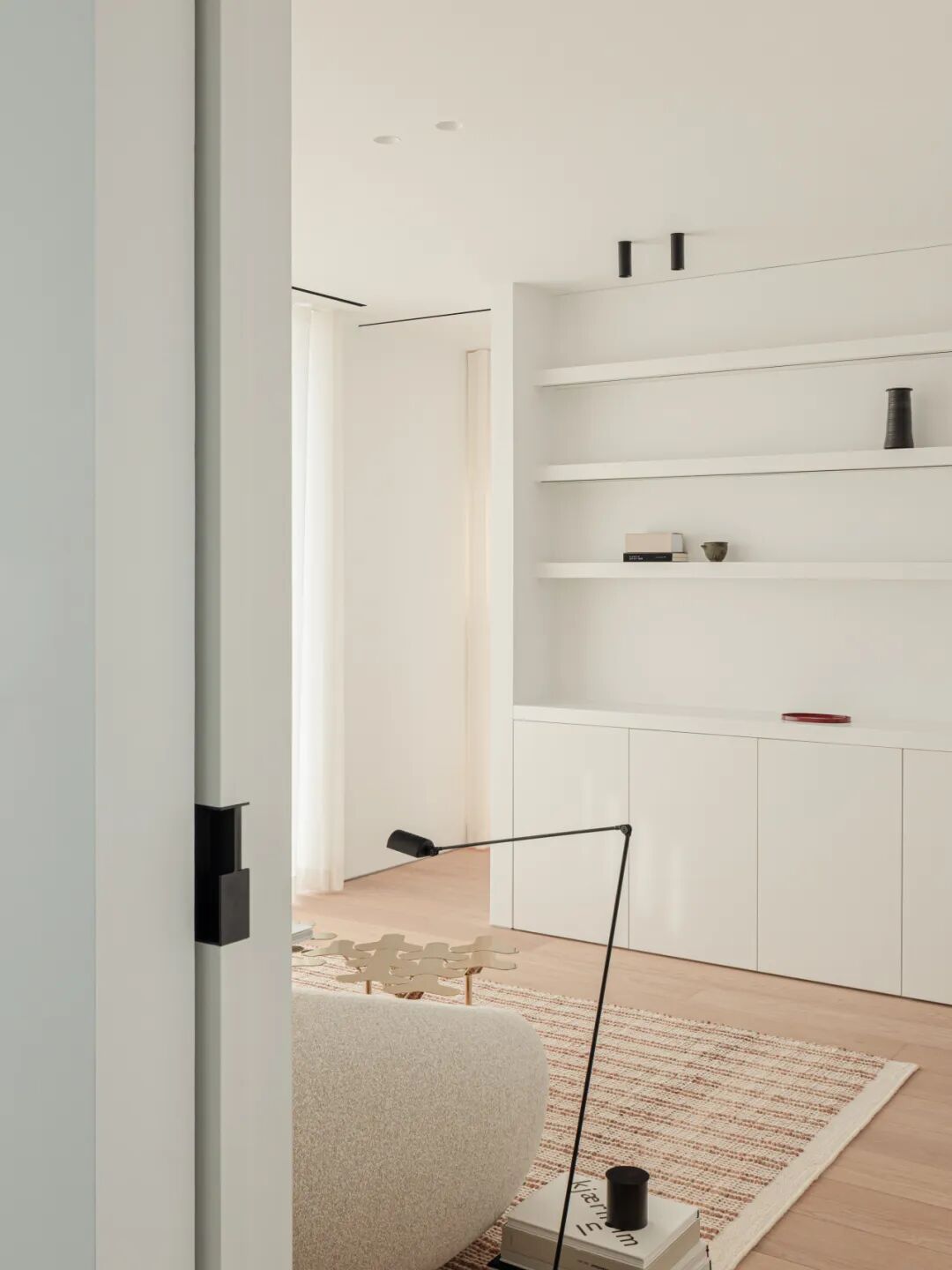 从门框视角看卧室休闲区，置物架与落地灯