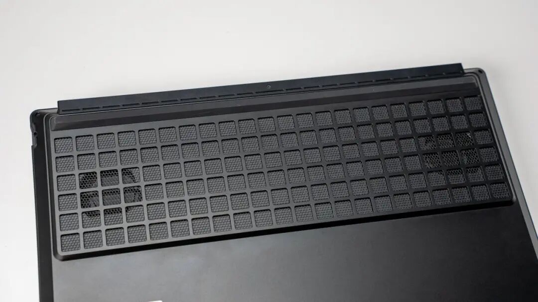 笔记本电脑底部网格状散热格栅特写，可见内部风扇叶片轮廓