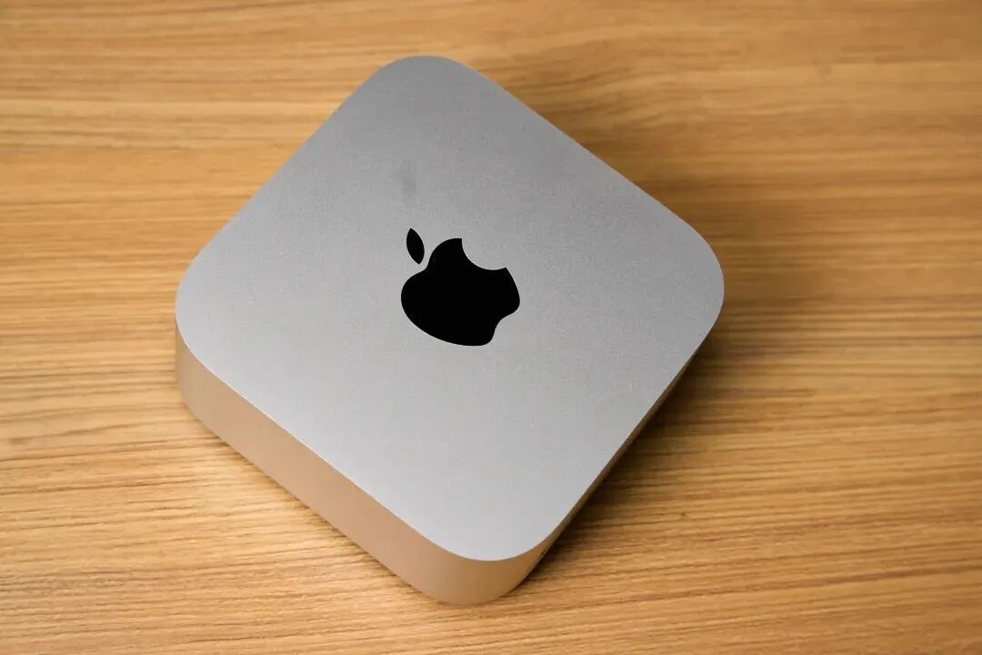 银色Mac mini主机放置在木纹桌面上