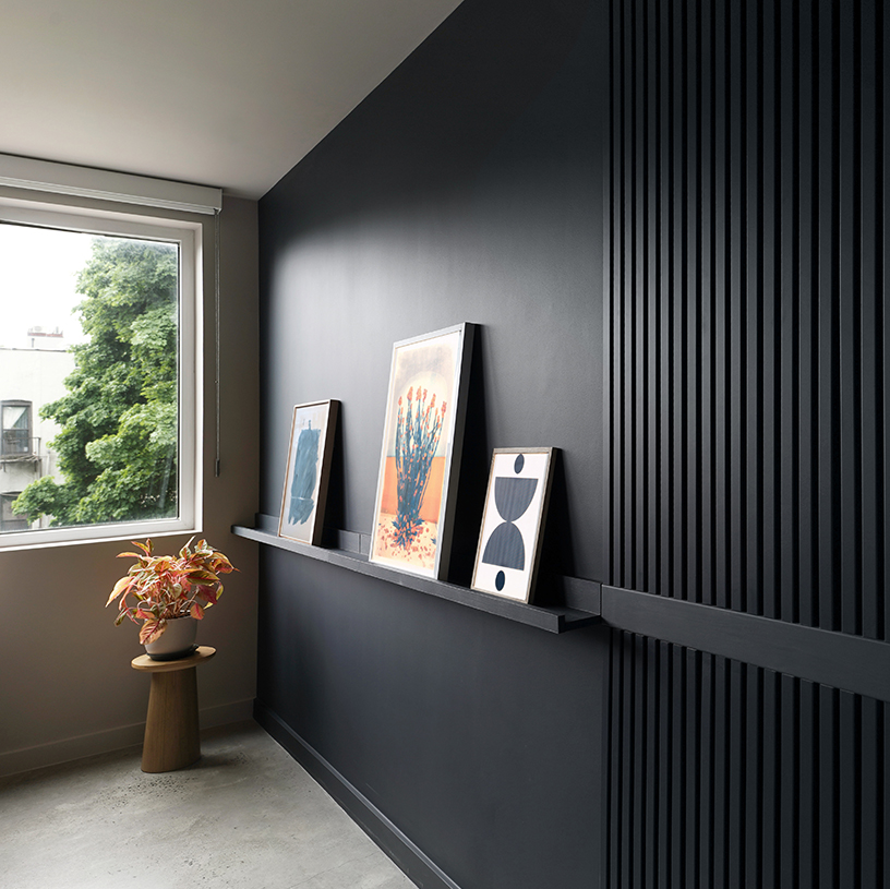 室内一角，黑色置物架装饰画与窗外绿植