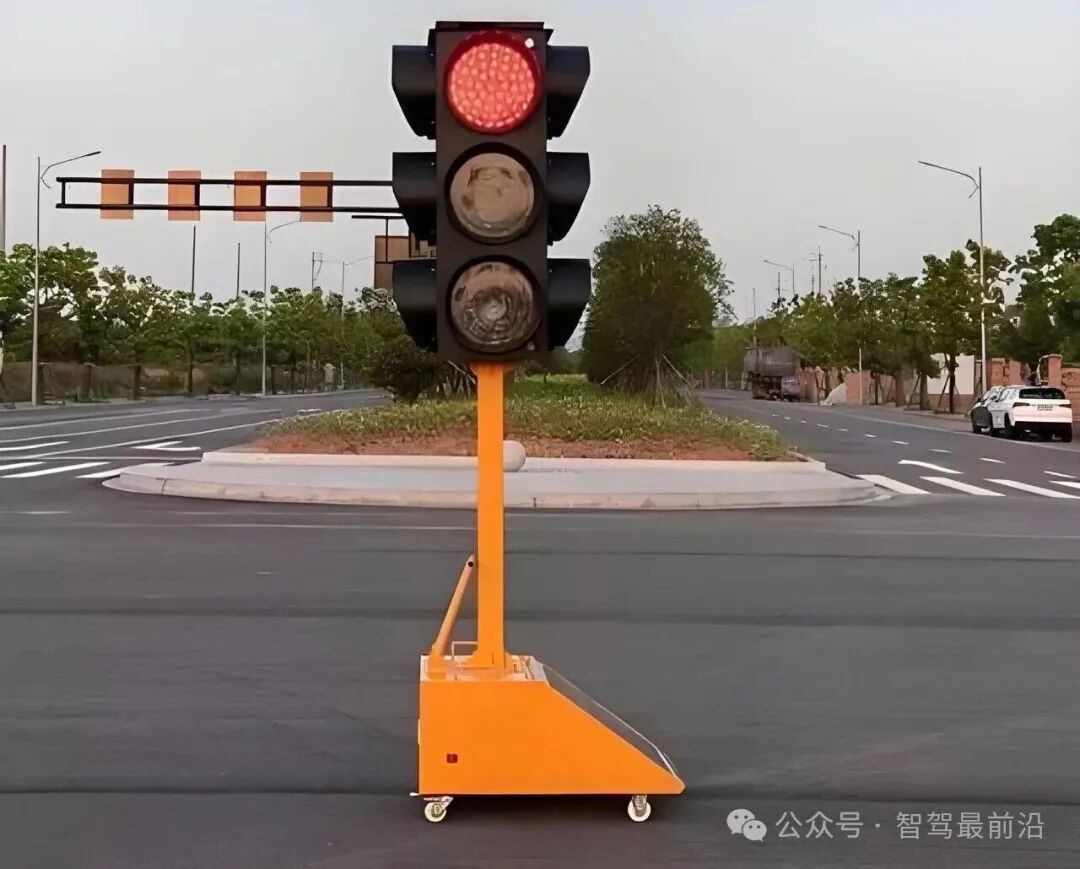 一个安装在橙色移动底座上的临时交通信号灯,红灯亮起,位于道路交叉口中央