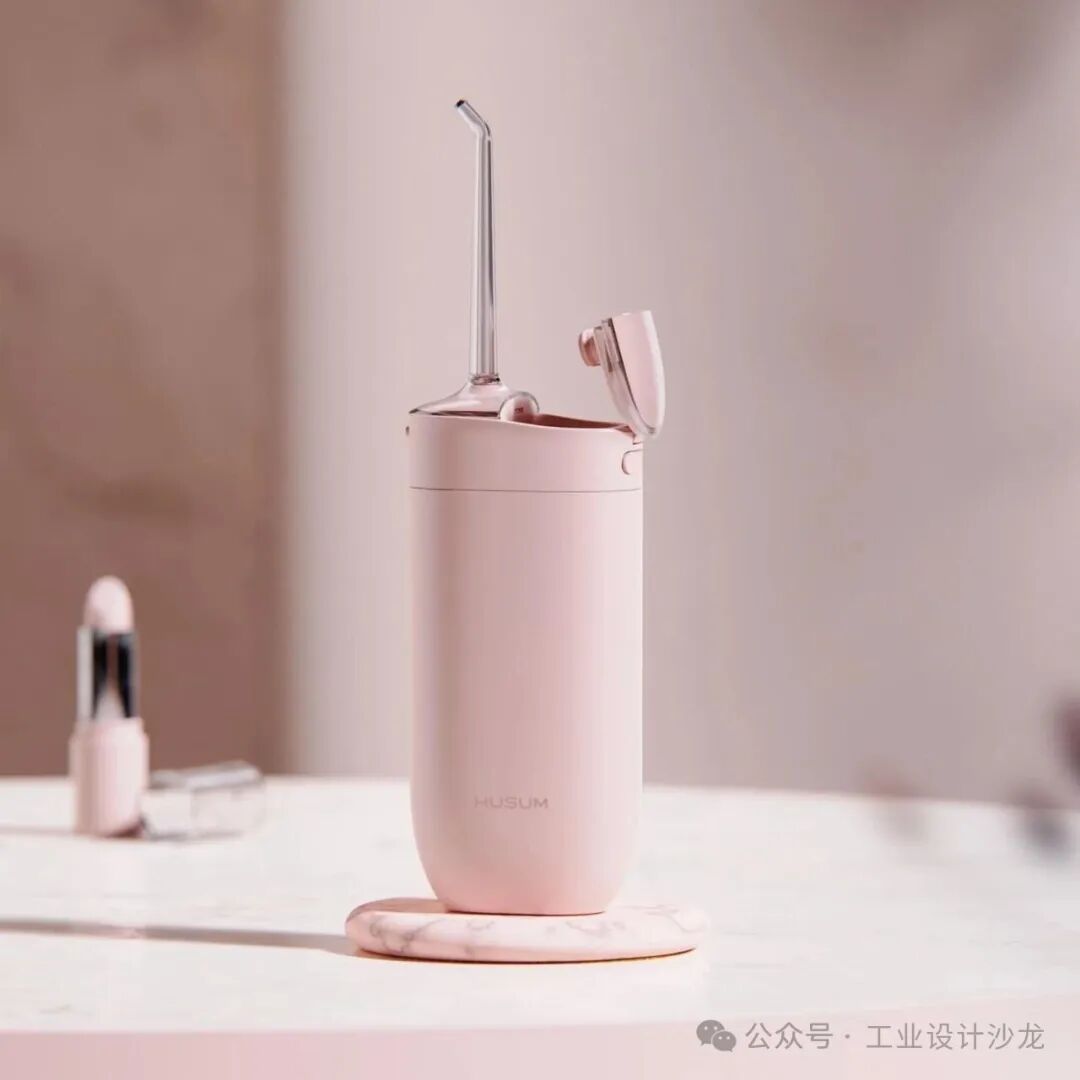 粉色电动冲牙器置于大理石底座上，机身印有 HUSUM 品牌标识