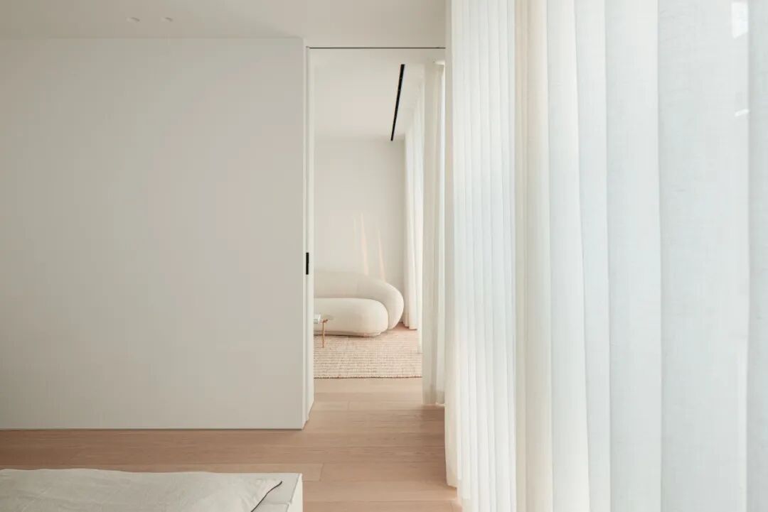 从门缝看入带云朵沙发的极简卧室