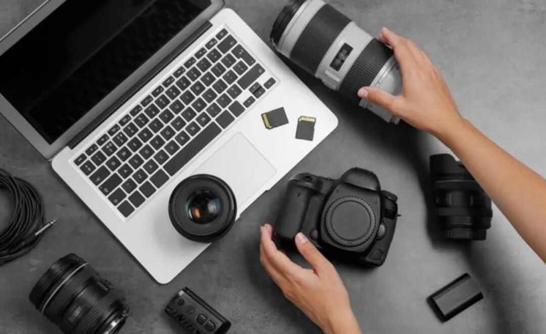摄影师工作台摆放着相机镜头和笔记本电脑