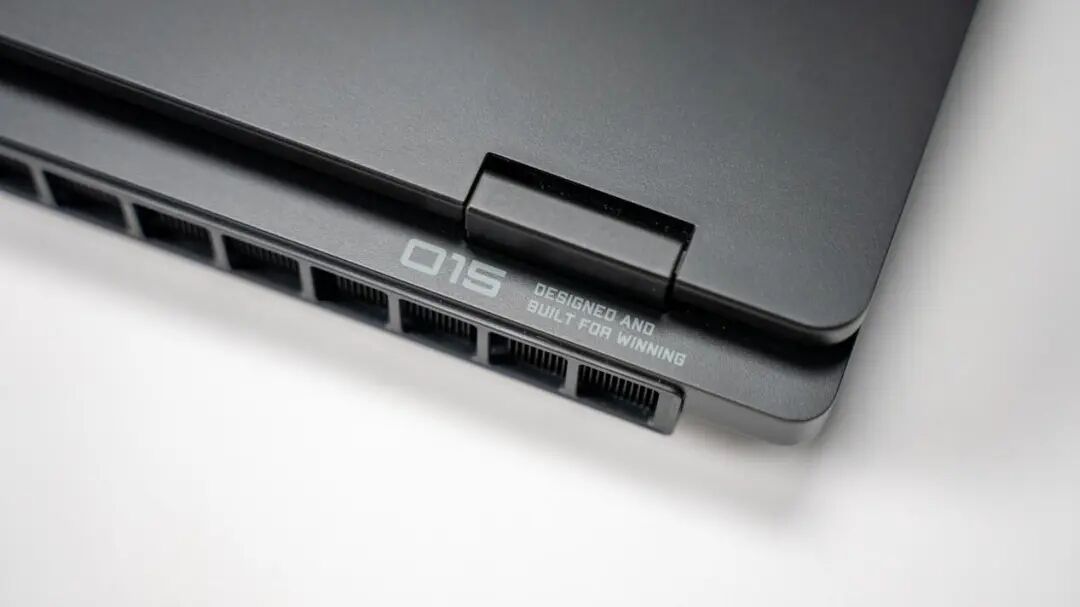 黑色笔记本电脑侧边散热格栅特写，印有白色‘Q15’及品牌标语