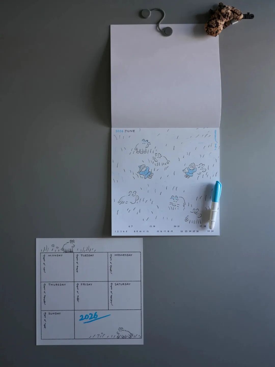 冰箱门贴手绘日历：2026年6月，蓝白笔手绘小人与雨滴，金属夹固定