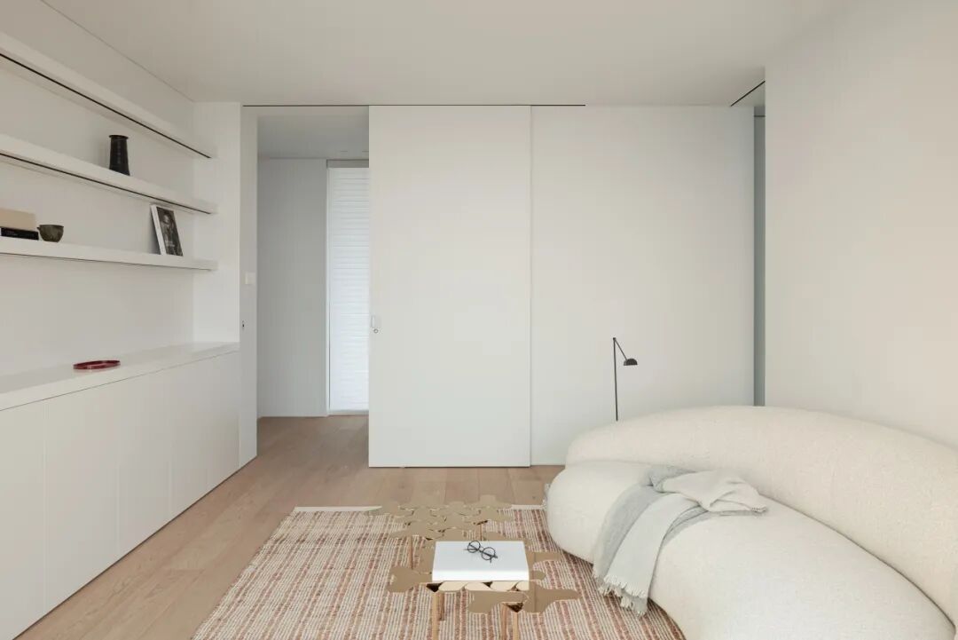 卧室外的休闲阅读区，弧形沙发与落地灯