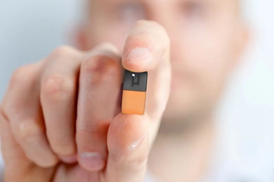 一只手捏着一个小型矩形电子元件，上半部分为黑色