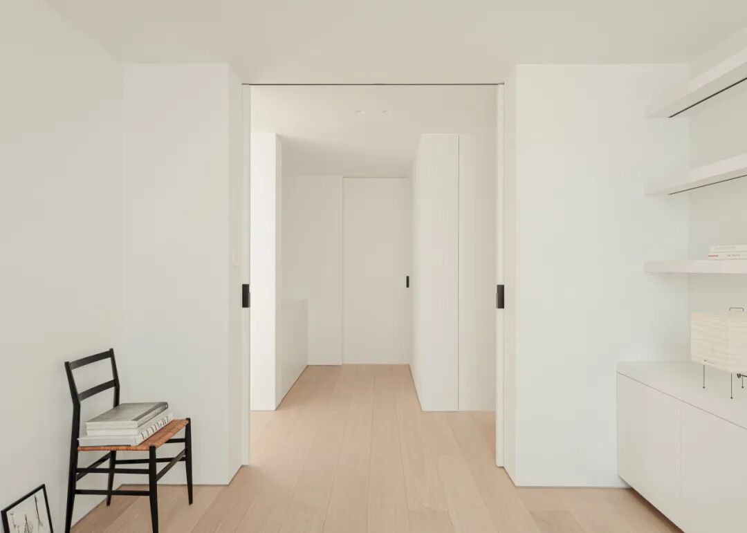 极简风格角落，书架与白色纸灯笼台灯