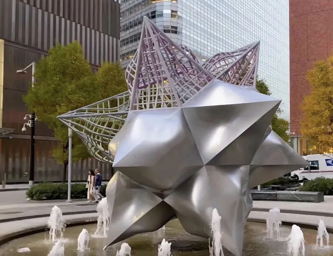 弗兰克·斯特拉的大型户外金属雕塑《贾斯珀的裂星》,矗立于现代建筑前的喷泉中