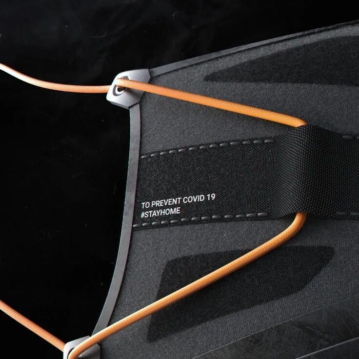 黑色织物材质局部，带有橙色弹性绳索与印有TO PREVENT COVID 19 #STAYHOME字样的织带