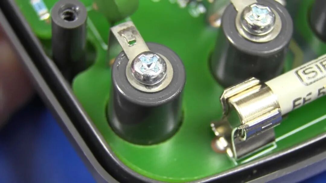 插孔固定方式特写:单颗螺丝压住弯折金属片,金属片直接焊接至 PCB,无防松垫圈设计