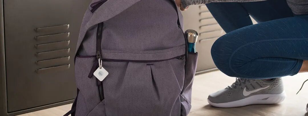 一名穿着蓝色紧身裤和灰色运动鞋的人蹲在金属储物柜旁