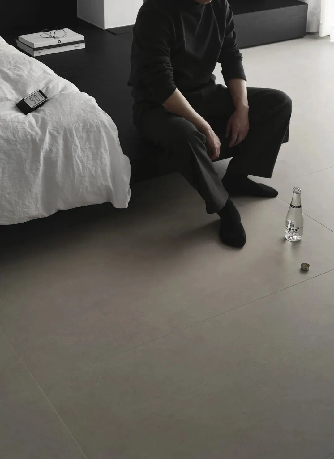 人物蹲坐于床边