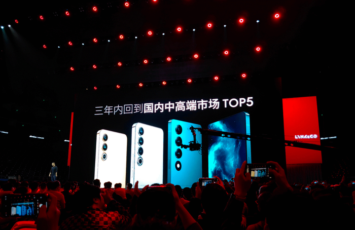 魅族发布会现场，屏幕上显示“三年内回到国内中高端市场TOP5”