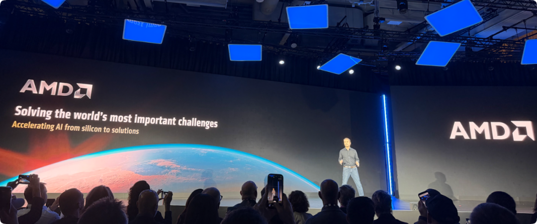 AMD 发布会现场,Jack Huynh 登台介绍 AMD 加速 AI 的策略,背景屏显示 Solving the world's most important challenges