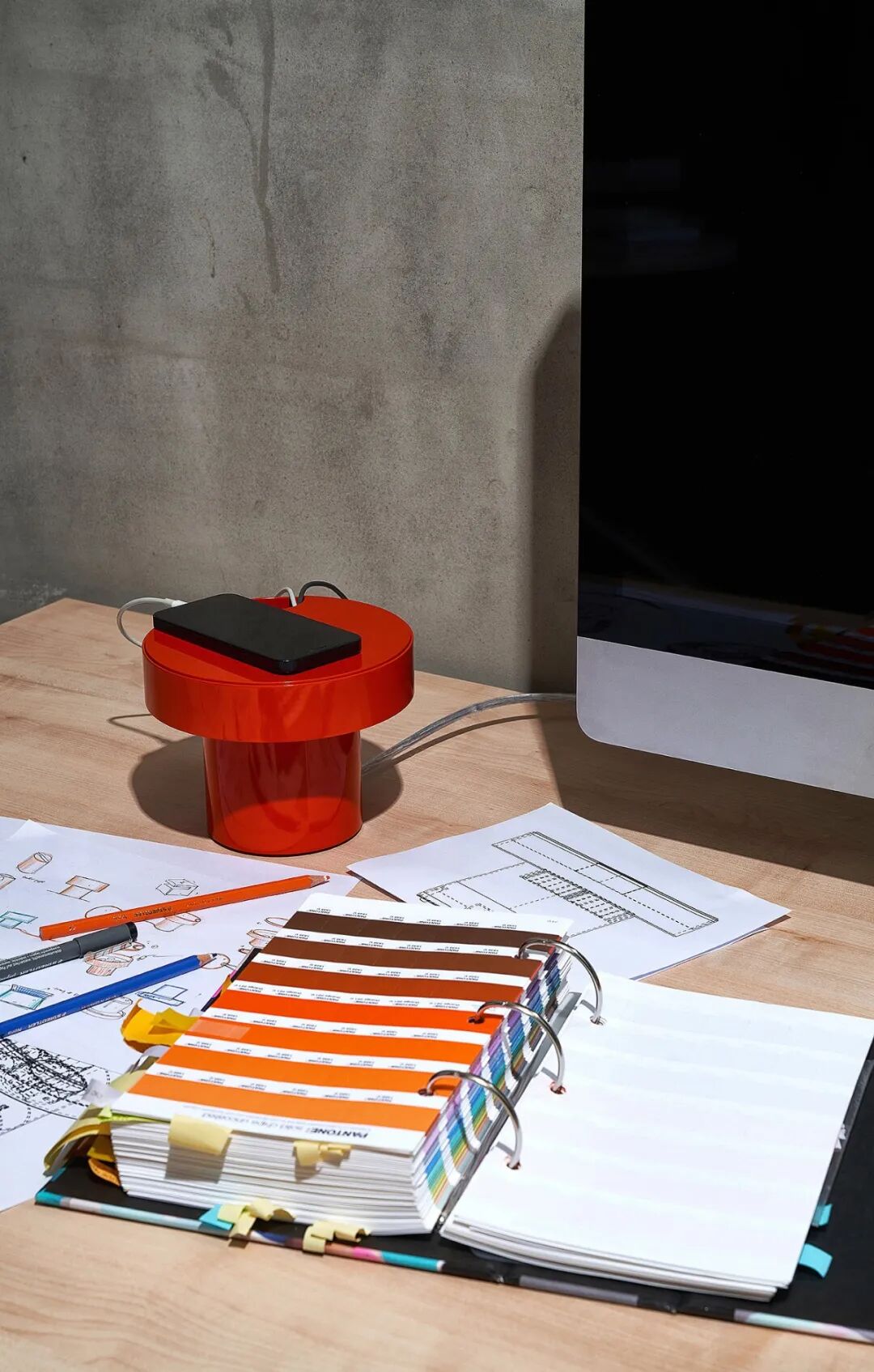 图片展示了一个工作台的场景，桌面上有一个红色的无线充电器