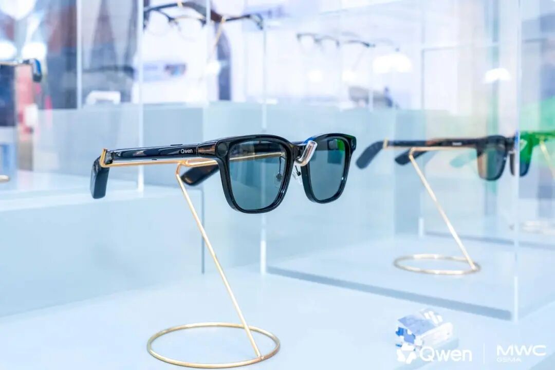 展示在玻璃展柜中的千问AI眼镜原型，镜腿上有Qwen品牌标识