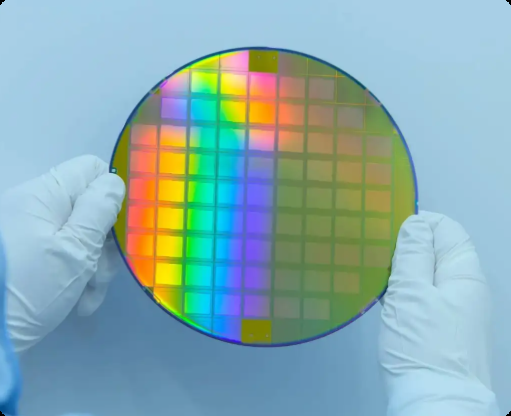 技术人员手持背面呈现彩虹光泽的晶圆