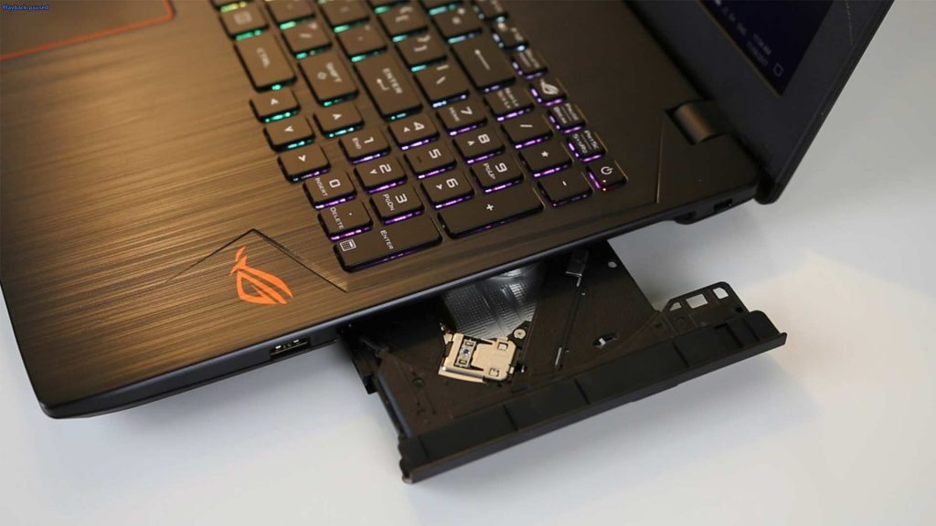 一台黑色金属拉丝质感的ROG游戏笔记本电脑，右侧光驱托盘弹出