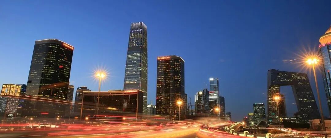 黄昏时分,北京CBD城市天际线灯火通明,央视总部大楼与国贸建筑群在深蓝天幕下形成动感光轨