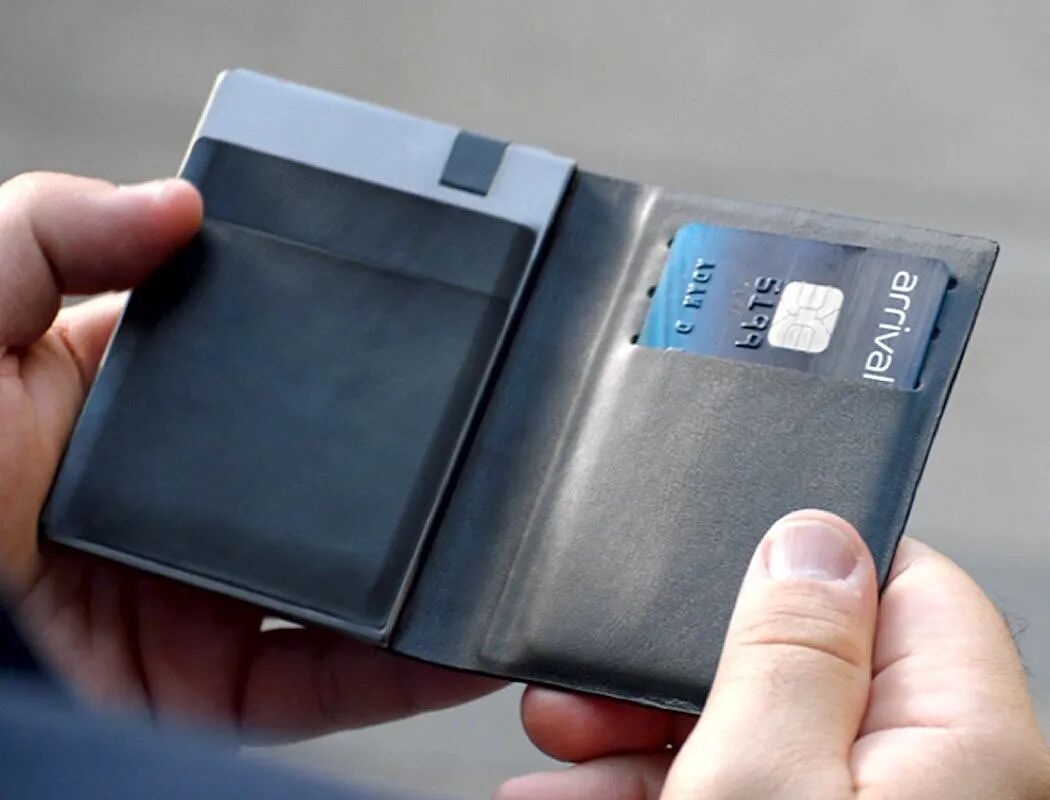 一只手拿着一个打开的黑色皮质钱包，钱包内侧有一个卡槽