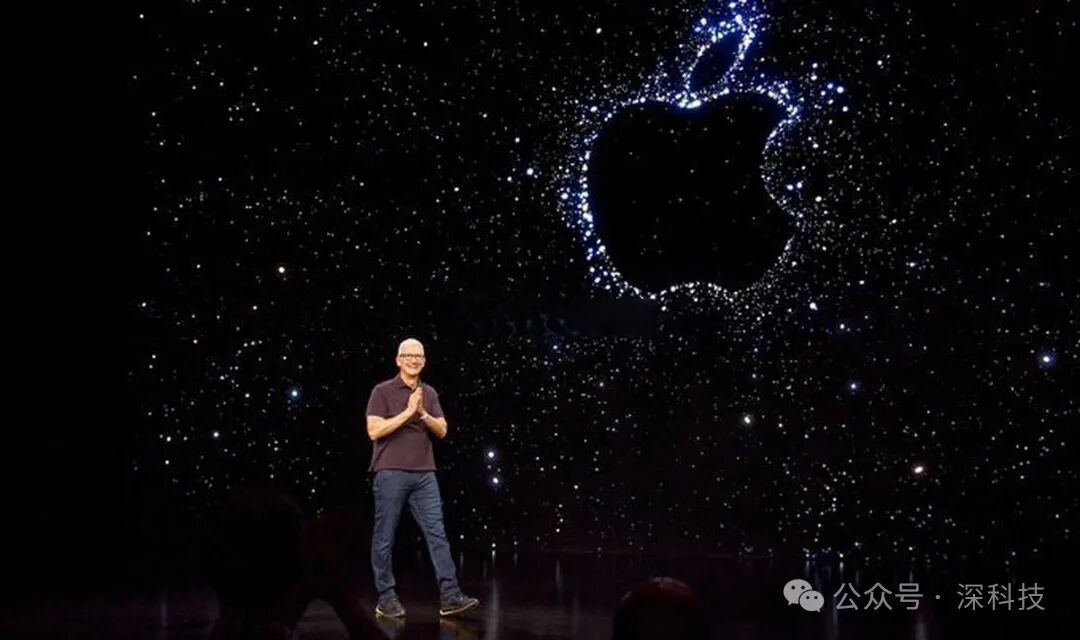 戴眼镜的白发演讲者站在有苹果LOGO的星空背景舞台前